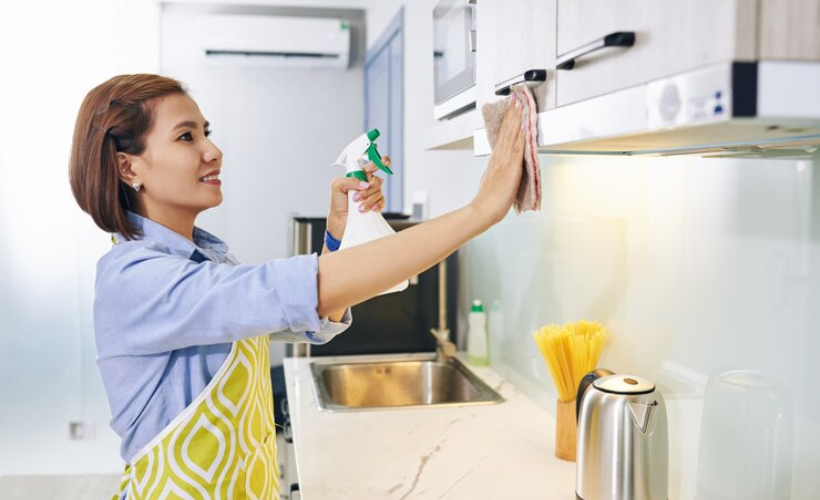 A housewife cleaning kitchen cabinets.